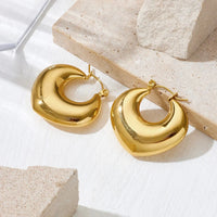 Aferando anti-tarnish chunky puffy gold hoop earrings in a soft heart shape with click-top closure, on a stone surface