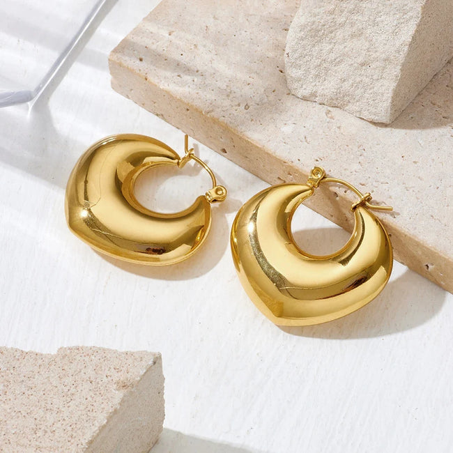 Aferando anti-tarnish chunky puffy gold hoop earrings in a soft heart shape with click-top closure, on a stone surface