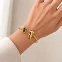 Aferando anti-tarnish gold open cuff bangle worn on the wrist, with an emerald-green stone and a puffy gold bean end