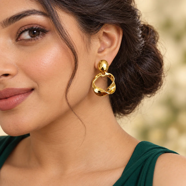 Aferando anti-tarnish molten gold twist drop earring worn by a woman with her hair in a low bun, green top