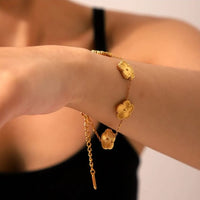 Anti-tarnish 18K gold plated four leaf clover charm bracelet worn on wrist — gold stainless steel stackable bracelet for women